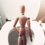 brown wooden mannequin on white ceramic toilet bowl