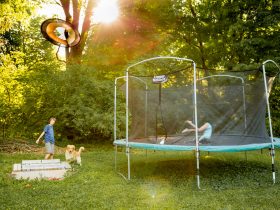 two children playing on a trampoline in a yard