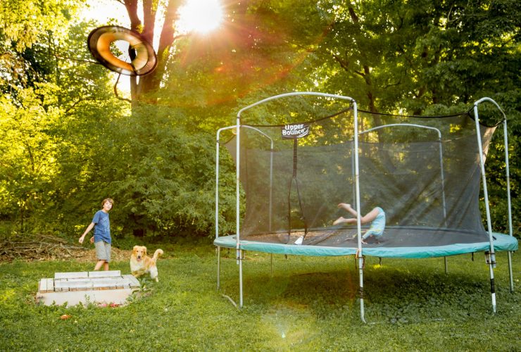 two children playing on a trampoline in a yard