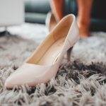 Elegante witte bruidsschoenen met lage hak op een houten ondergrond