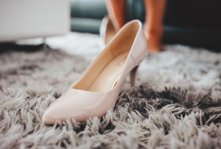 Elegante witte bruidsschoenen met lage hak op een houten ondergrond