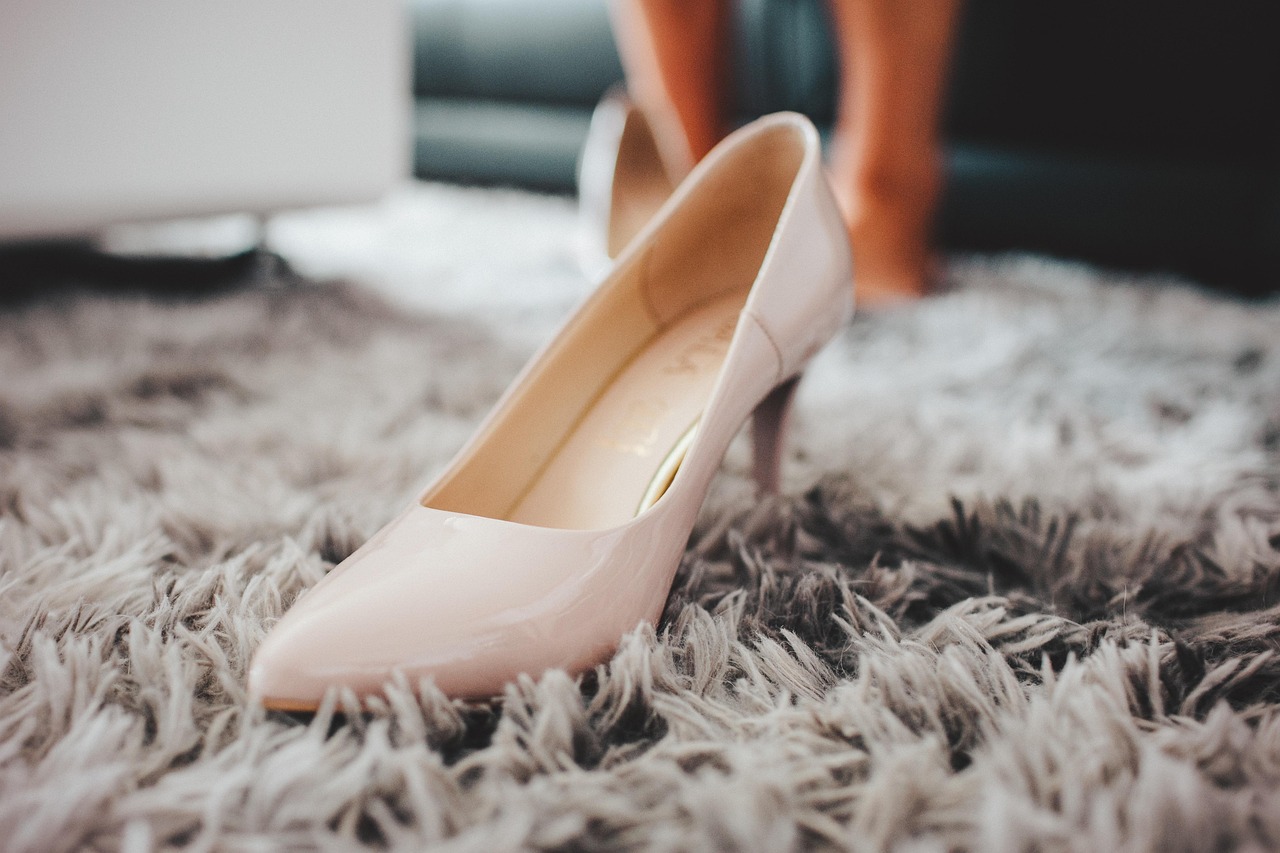 Elegante witte bruidsschoenen met lage hak op een houten ondergrond