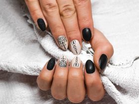 Handen met beschadigde nagels naast potjes met natuurlijke ingrediënten zoals olijfolie en honing voor een DIY nagelbehandeling