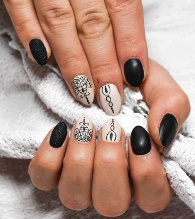 Handen met beschadigde nagels naast potjes met natuurlijke ingrediënten zoals olijfolie en honing voor een DIY nagelbehandeling