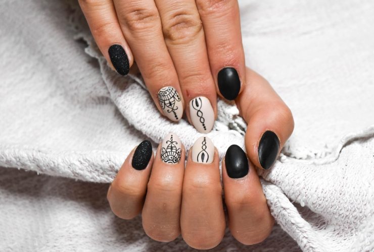 Handen met beschadigde nagels naast potjes met natuurlijke ingrediënten zoals olijfolie en honing voor een DIY nagelbehandeling