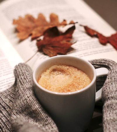 Gelaagde gouden kettingen gedragen over een warme herfsttrui