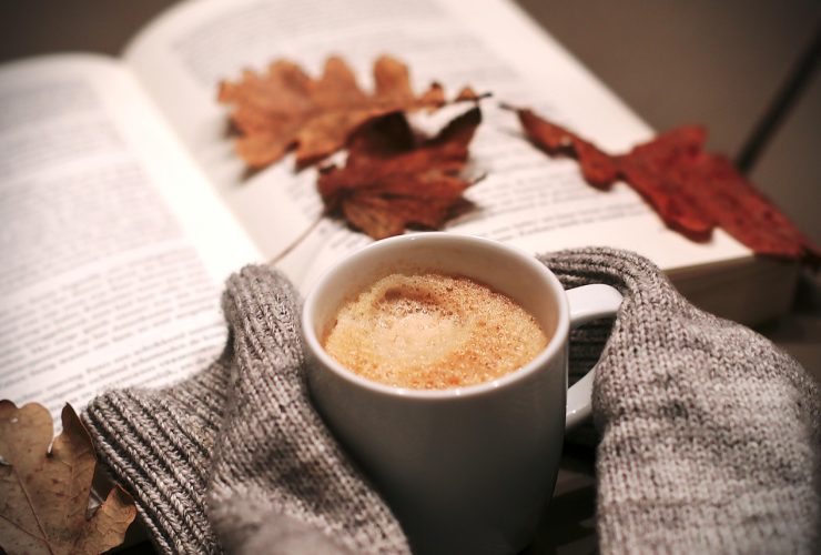 Gelaagde gouden kettingen gedragen over een warme herfsttrui