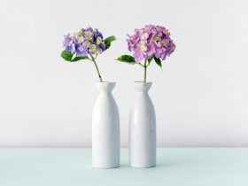 Drie vazen van verschillende materialen op een houten plank in een modern interieur