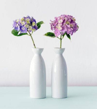 Drie vazen van verschillende materialen op een houten plank in een modern interieur