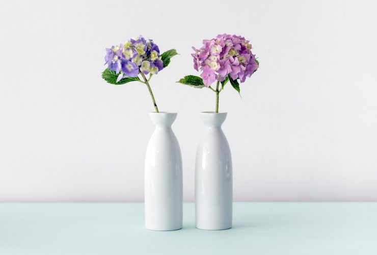 Drie vazen van verschillende materialen op een houten plank in een modern interieur