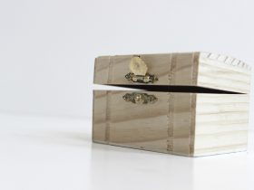 Een open sieradendoos met verschillende armbanden, ringen en kettingen op een houten ondergrond