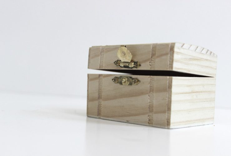 Een open sieradendoos met verschillende armbanden, ringen en kettingen op een houten ondergrond