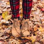 Gesloten herfstlaarzen aan vrouwelijke voeten op houten vloer