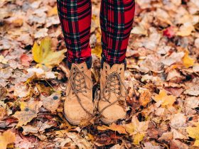 Gesloten herfstlaarzen aan vrouwelijke voeten op houten vloer