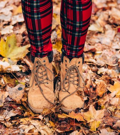 Gesloten herfstlaarzen aan vrouwelijke voeten op houten vloer