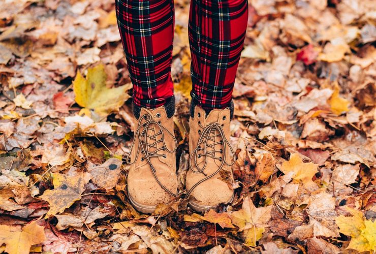 Gesloten herfstlaarzen aan vrouwelijke voeten op houten vloer