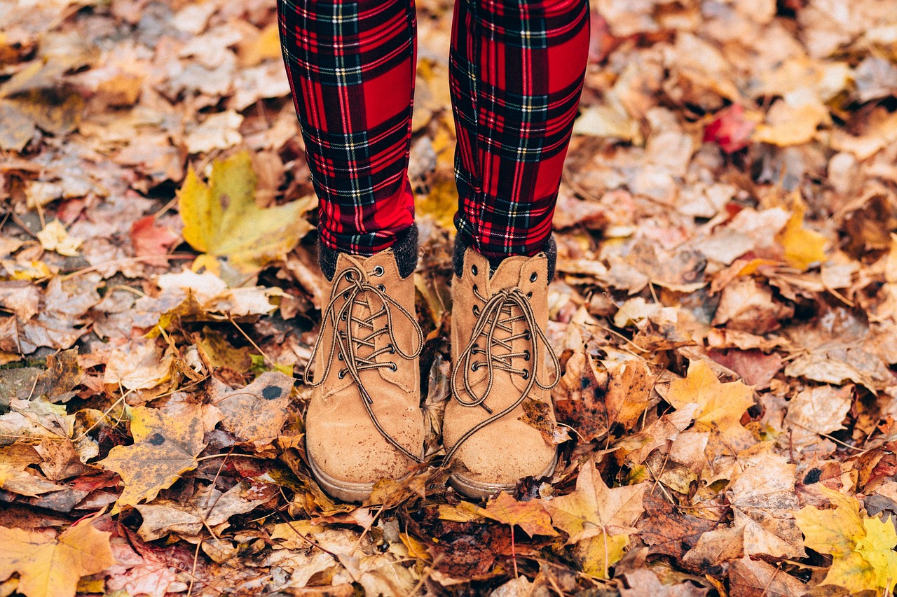 Gesloten herfstlaarzen aan vrouwelijke voeten op houten vloer