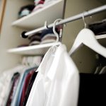 Vrouw die kleding bekijkt in haar kledingkast en nadenkt over haar persoonlijke stijl