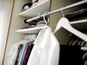 Vrouw die kleding bekijkt in haar kledingkast en nadenkt over haar persoonlijke stijl