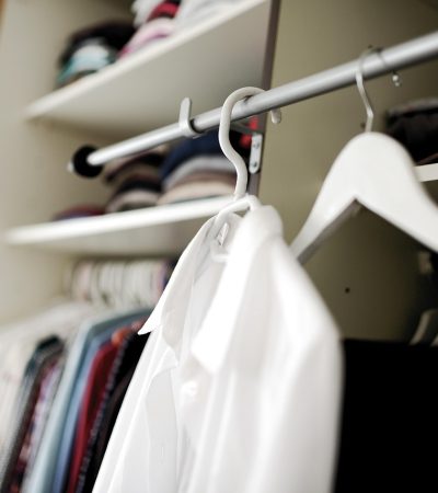 Vrouw die kleding bekijkt in haar kledingkast en nadenkt over haar persoonlijke stijl