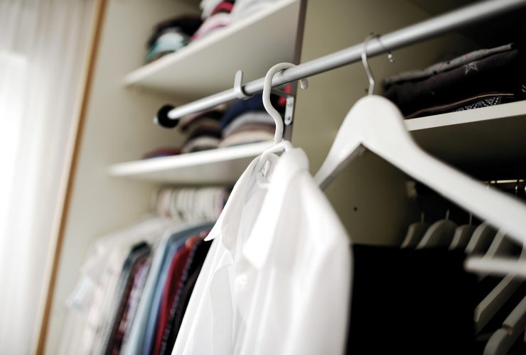 Vrouw die kleding bekijkt in haar kledingkast en nadenkt over haar persoonlijke stijl