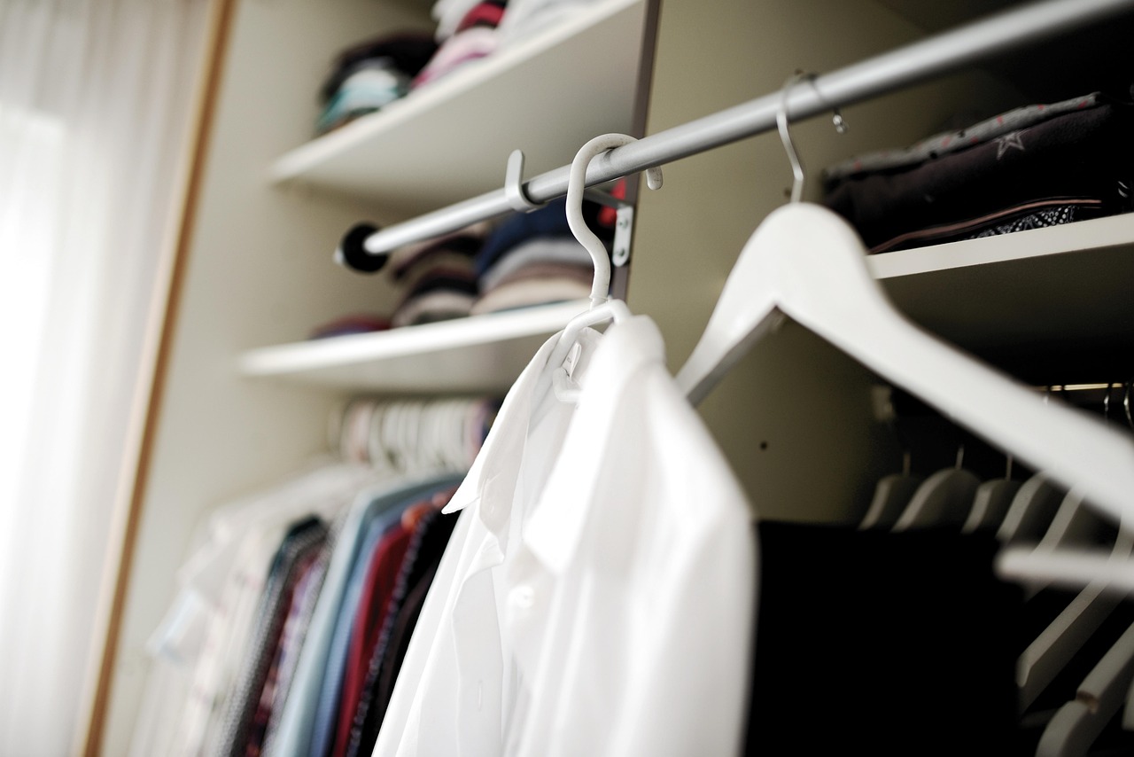 Vrouw die kleding bekijkt in haar kledingkast en nadenkt over haar persoonlijke stijl