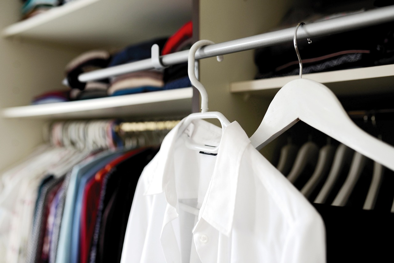 Vrouw die kleding kiest uit een overzichtelijke kledingkast voor een hybride werkdag